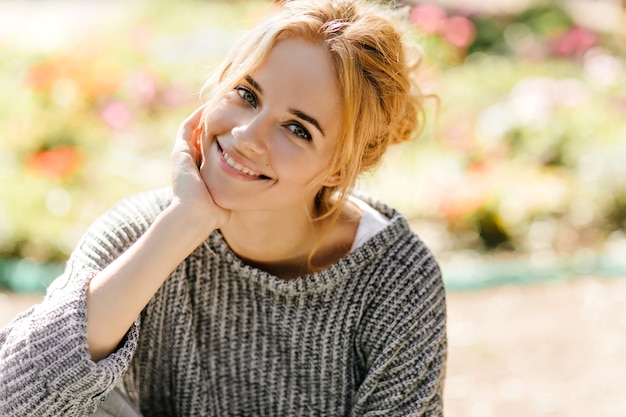 Portrait of green-eyed redhead woman posing sitting in green house