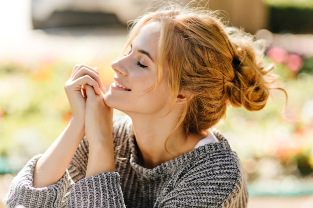 Portrait of green-eyed redhead woman posing sitting in green house