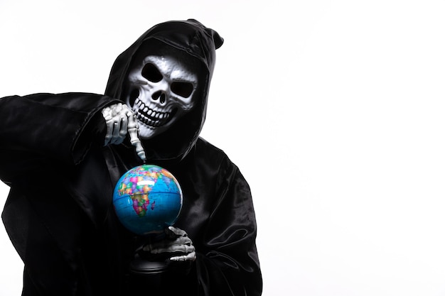 Portrait of grim reaper in black clothes with little globe on white