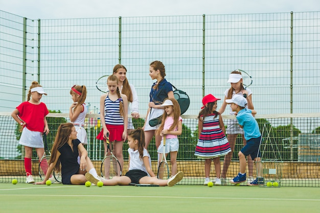 Портрет группы девушек как теннисистки с теннисной ракеткой на фоне зеленой травы открытого корта