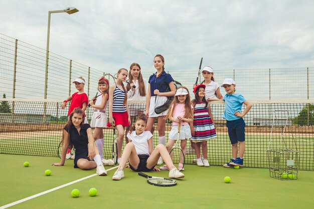 テニスラケットを保持しているテニス選手としての女の子のグループの肖像画