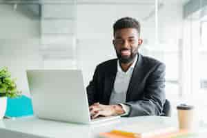 Free photo portrait of handsome african black young business man working on laptop at office desk