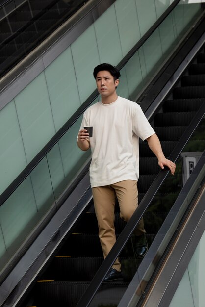 Portrait of handsome asian man having coffee outdoors in the city