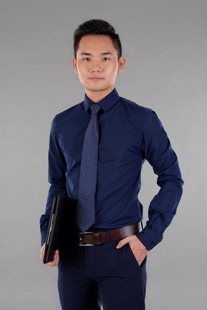Portrait of handsome Asian man one hand holding a clipboard another in pocket looking at camera