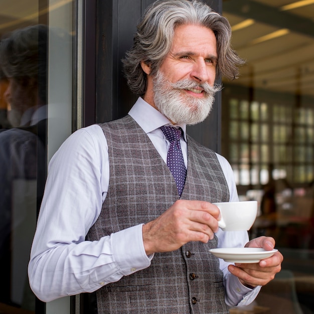 Foto gratuita ritratto del maschio barbuto bello che gode del caffè