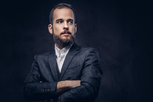 Portrait of handsome bearded stylish male, wearing an elegant suit on a dark background.