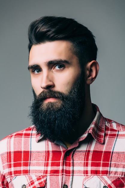 Portrait of handsome bearded young man isolated on gray wall