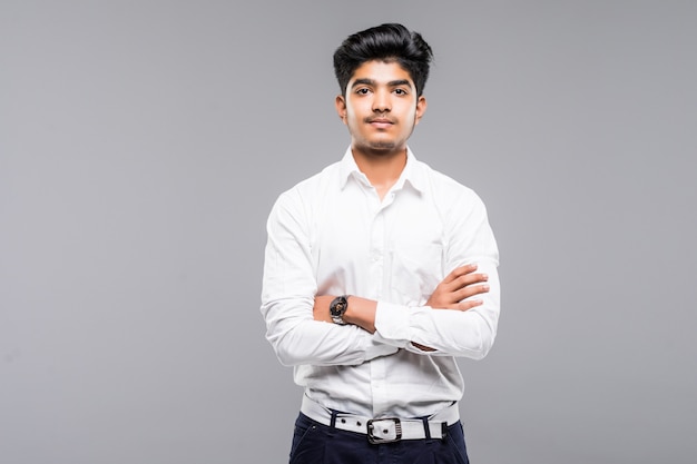 Portrait of handsome businessman standing in crossed hands isolated on gray wall.