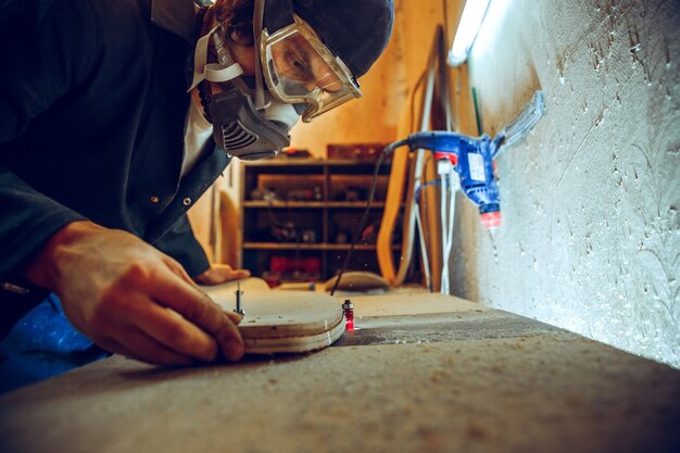 Portrait of handsome carpenter working with wooden skate at workshop