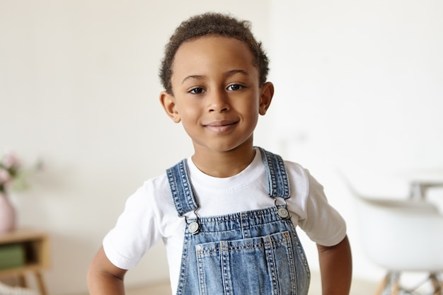 Portrait of handsome cheerful little boy of African origin posing indoors