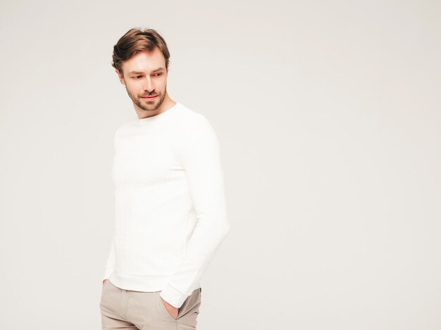 Portrait of handsome confident hipster lumbersexual businessman model wearing casual white sweater and trousers