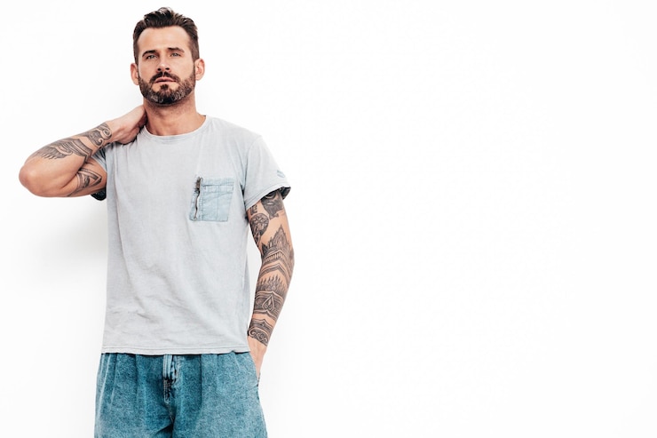 Free Photo portrait of handsome confident stylish hipster lambersexual model sexy man dressed in tshirt and jeans fashion male isolated on white wall in studio