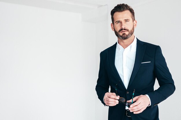 Portrait of handsome confident stylish hipster lambersexual model Sexy modern man dressed in black elegant suit Fashion male posing in studio on white background