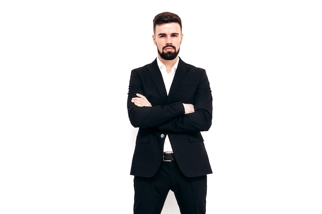 Portrait of handsome confident stylish hipster lambersexual model Sexy modern man dressed in elegant black suit Fashion male posing in studio near white wall Isolated