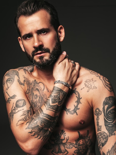 Ritratto di modello lambersexual bello fiducioso elegante hipster uomo moderno sexy torso nudo con tatuaggiuomo di moda in posa in studio su sfondo scuro