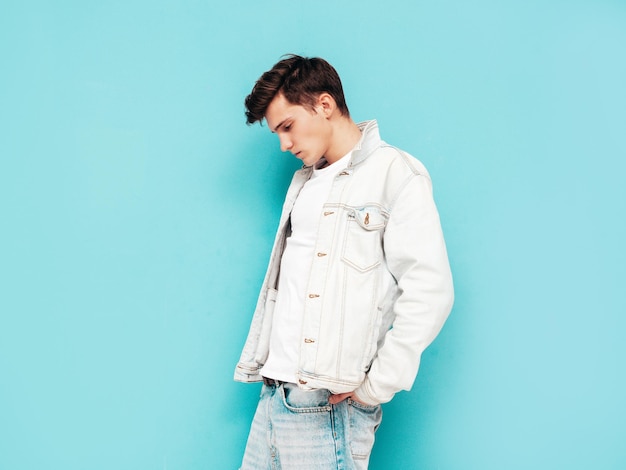 재킷과 청바지를 입은 잘생긴 자신감 있는 세련된 힙스터 램버섹슈얼 모델남자의 초상화 파란 벽 근처 스튜디오에서 포즈를 취하는 패션 남성