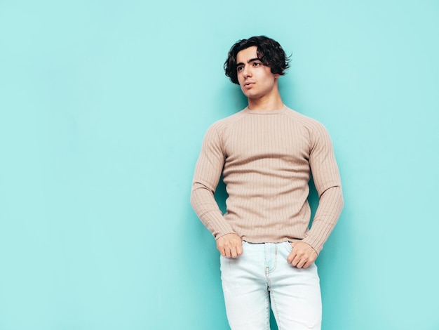 Portrait of handsome confident stylish hipster lambersexual modelMan dressed in summer clothes Fashion male isolated in studio Posing near blue wall