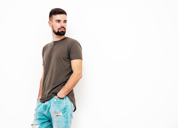 Portrait of handsome confident stylish hipster lambersexual modelMan dressed in Tshirt and jeans Fashion male isolated on white wall in studio