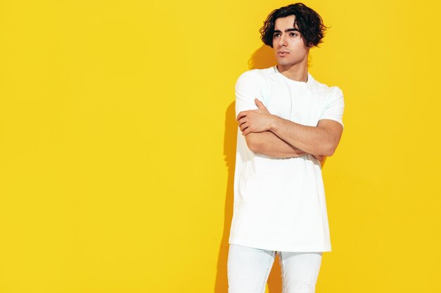 잘생긴 자신감 있는 세련된 힙스터 램버섹슈얼 모델의 초상 사이즈가 큰 티셔츠와 청바지를 입은 섹시한 남자 스튜디오에서 격리된 패션 남성 노란색 벽 근처에서 포즈를 취하는