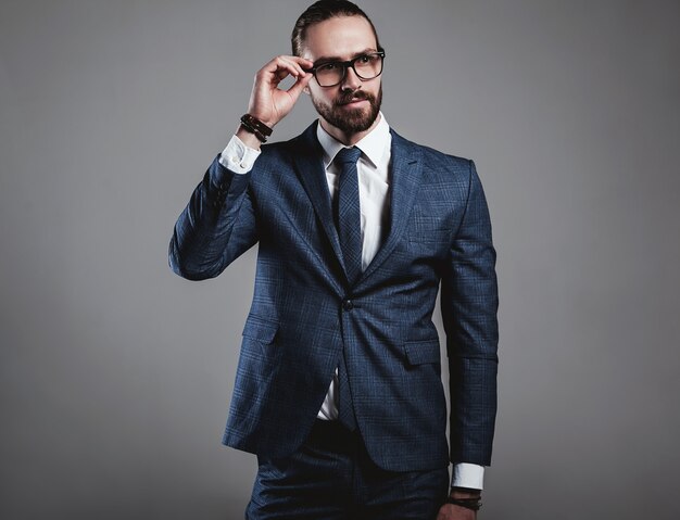 Portrait of handsome fashion businessman model dressed in elegant blue suit with glasses