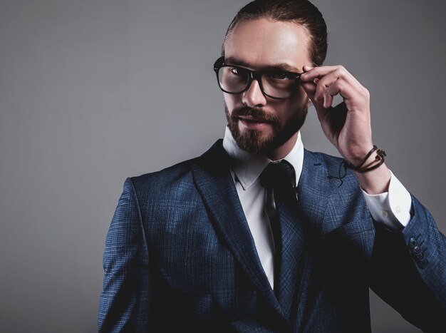 Portrait of handsome fashion businessman model dressed in elegant blue suit with glasses