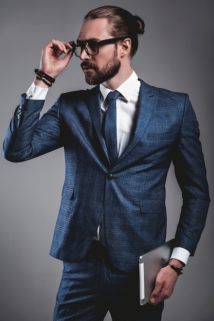 Portrait of handsome fashion businessman model dressed in elegant blue suit with glasses