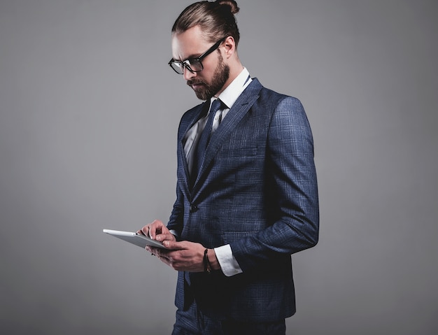 Portrait of handsome fashion businessman model dressed in elegant blue suit with glasses