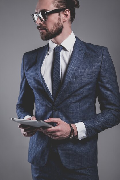 Portrait of handsome fashion businessman model dressed in elegant blue suit with glasses