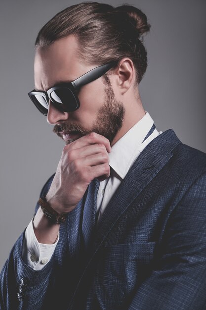 Portrait of handsome fashion businessman model dressed in elegant blue suit with glasses