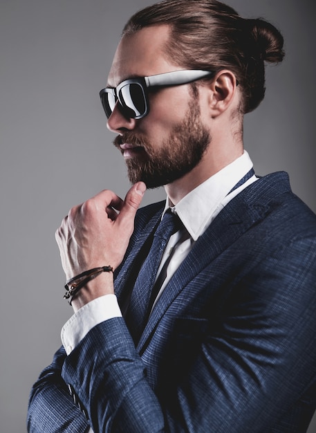 Portrait of handsome fashion businessman model dressed in elegant blue suit with glasses