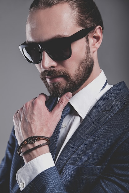 portrait of handsome fashion businessman  model dressed in elegant blue suit with sunglasses