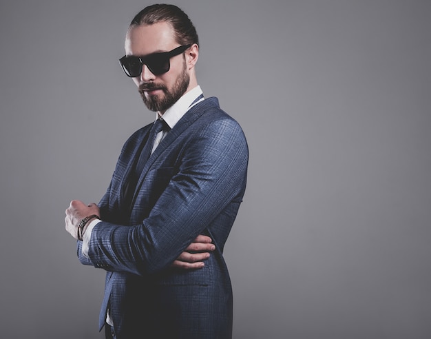 portrait of handsome fashion businessman  model dressed in elegant blue suit with sunglasses