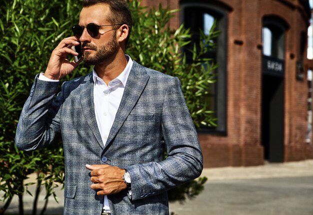 Portrait of handsome fashion businessman model dressed in elegant checkered suit posing on street