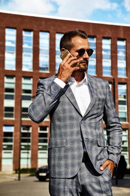 Portrait of handsome fashion businessman model dressed in elegant checkered suit posing on street