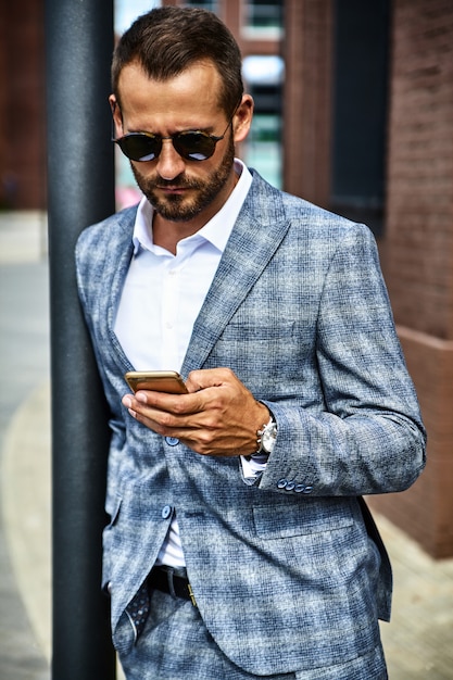 Il ritratto del modello bello dell'uomo d'affari di modo si è vestito in vestito a quadretti elegante che posa sulla via