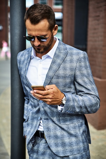 Portrait of handsome fashion businessman model dressed in elegant checkered suit posing on street