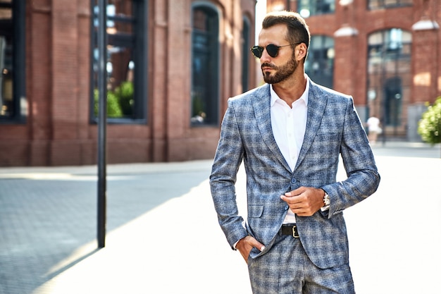 Portrait of handsome fashion businessman model dressed in elegant checkered suit posing on street