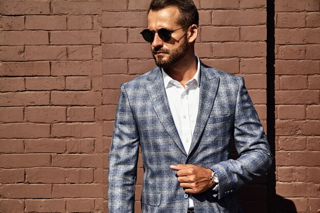 Portrait of handsome fashion businessman model dressed in elegant checkered suit posing on street