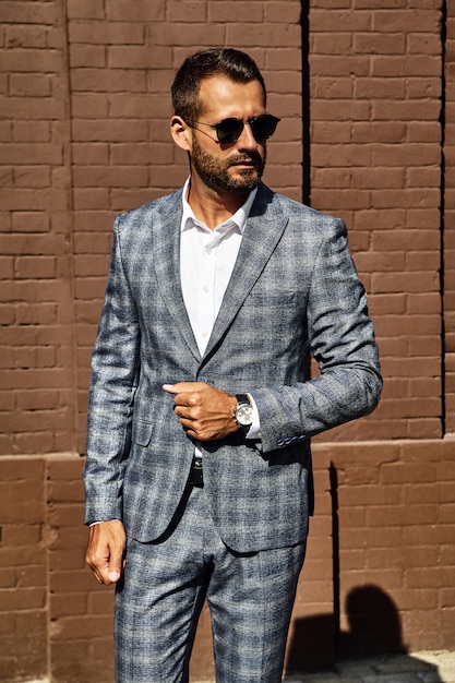 Free photo portrait of handsome fashion businessman model dressed in elegant checkered suit posing on street