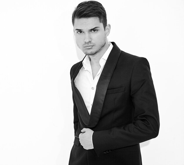 portrait of handsome fashion stylish businessman model dressed in elegant black classic suit posing. Metrosexual