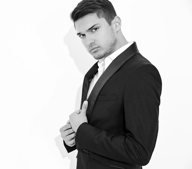 portrait of handsome fashion stylish businessman model dressed in elegant black classic suit posing. Metrosexual