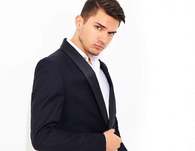 portrait of handsome fashion stylish businessman model dressed in elegant black classic suit posing. Metrosexual