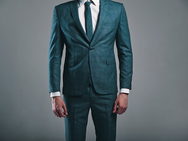 Портрет красивый модный стильный бизнесмен модель, одетый в элегантный зеленый костюм, позирует на сером фоне в студии