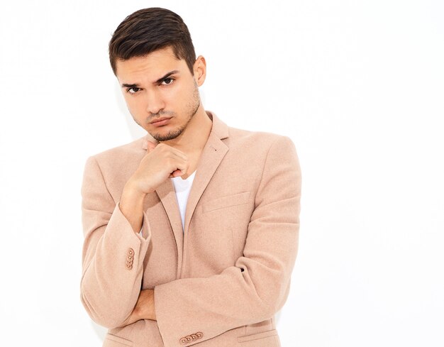 portrait of handsome fashion stylish businessman model dressed in elegant light pink suit posing. Metrosexual