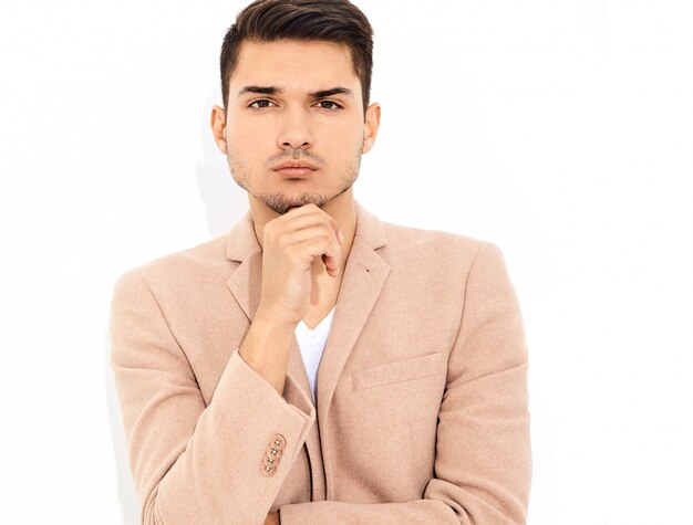 portrait of handsome fashion stylish businessman model dressed in elegant light pink suit posing. Metrosexual