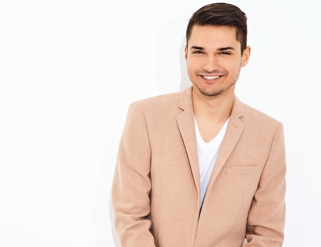 portrait of handsome fashion stylish businessman model dressed in elegant light pink suit posing. Metrosexual