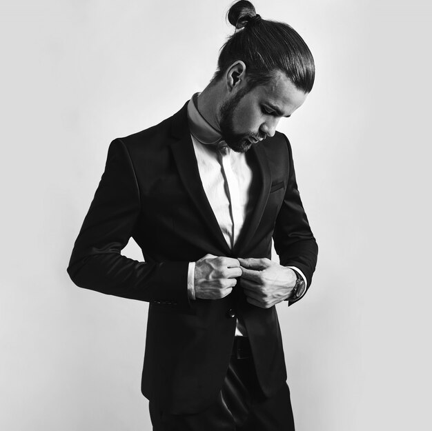 portrait of handsome fashion stylish hipster businessman model dressed in elegant black suit.