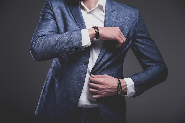 portrait of handsome fashion stylish hipster businessman model dressed in elegant blue suit on gray