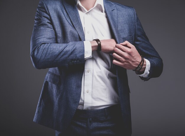 portrait of handsome fashion stylish hipster businessman model dressed in elegant blue suit on gray