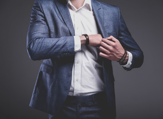 portrait of handsome fashion stylish hipster businessman model dressed in elegant blue suit on gray